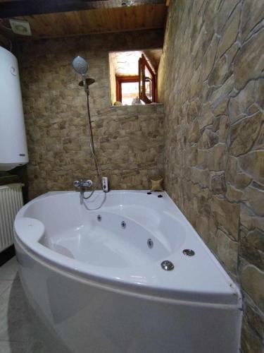 een badkamer met een bad en een stenen muur bij Pola vendégház in Miskolc