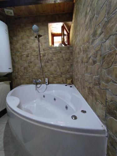 a bath tub in a bathroom with a stone wall at Pola vendégház in Miskolc
