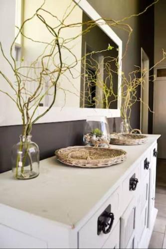 a white cabinet with a mirror and vases on it at Olive Grove on Provident in Cape Town