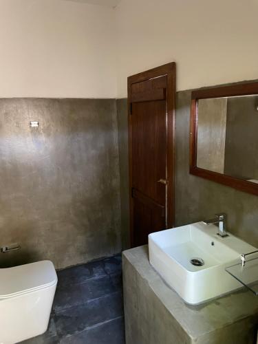 a bathroom with a sink and a toilet and a mirror at Ocean Vibe Srilanka in Arugam Bay