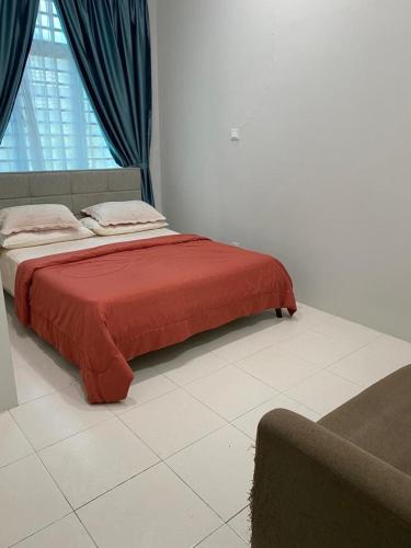 uma cama num quarto com um cobertor vermelho em Qaisara Homestay em Kampong Alor Gajah