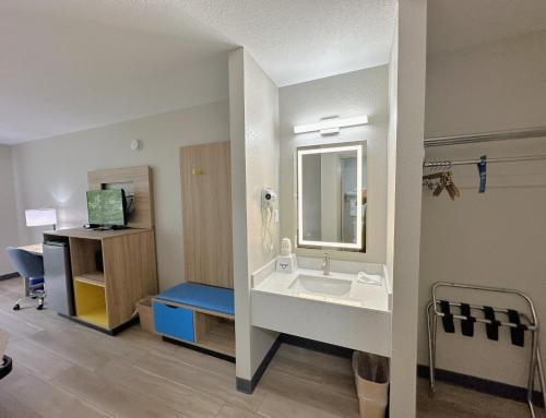 a room with a bathroom with a sink and a desk at Days Inn by Wyndham Holland in Holland