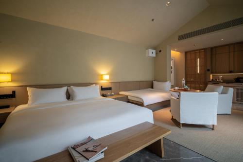 een slaapkamer met een groot wit bed en een keuken bij Jiangnan House Chaozhou in Chaozhou