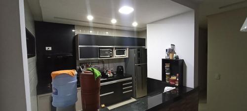 a kitchen with a black refrigerator and a microwave at CASA COMPARTILHADA PERTINHO DO PARQUE ACAUÃ em Garanhuns - Leia atentamente a descricão do imóvel in Garanhuns