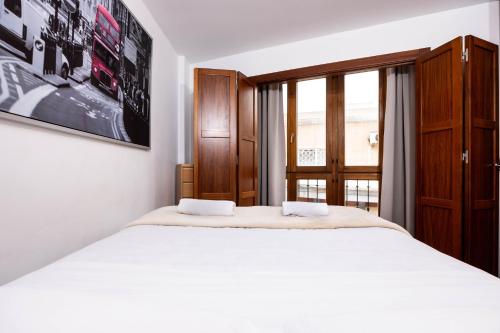 um quarto com uma grande cama branca e uma janela em Apartamentos Turísticos Distrito Romano em Cartagena