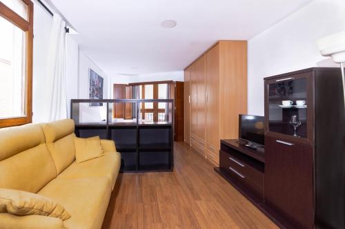 een woonkamer met een bank en een televisie bij Apartamentos Turísticos Distrito Romano in Cartagena