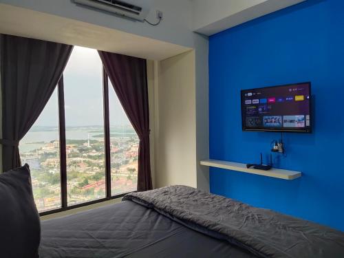 a bedroom with a blue wall and a large window at Comodo Apartemen Pollux Habibie Rooftop-SeaView in Batam Center