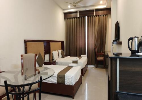 une chambre d'hôtel avec un lit, une table et une chaise dans l'établissement HOTEL REDLAS INN, à Sangāreddi
