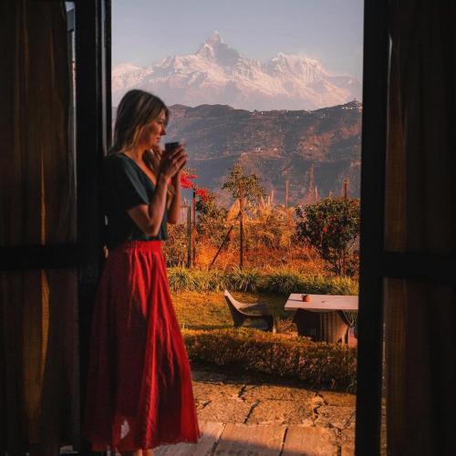 a woman standing outside a window looking at her cell phone at Raniban Retreat in Pokhara