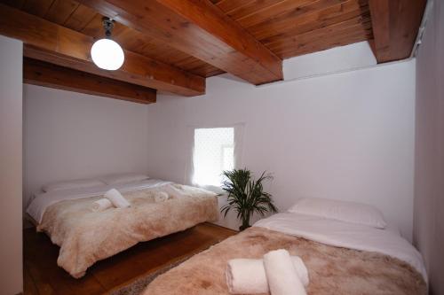 two beds in a room with white walls and wooden ceilings at Kulla Pracja Theth in Theth
