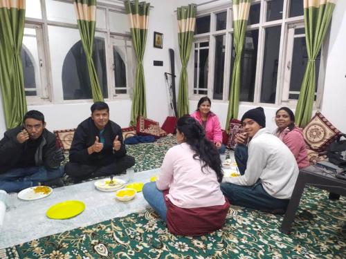 a group of people sitting around a table eating food at Elizabeth paying guest house Tangmarg gulmarg in Gulmarg