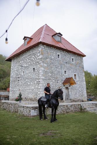 a man riding a horse in front of a building at Kulla Pracja Theth in Theth