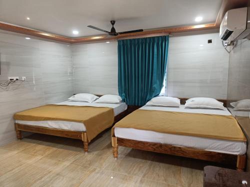 a bedroom with two beds and a blue curtain at SDD Grand in Tiruvannāmalai