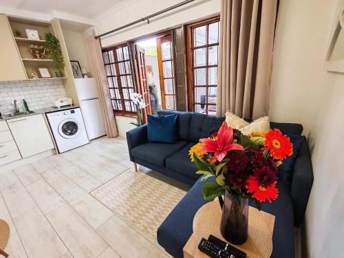 a living room with a blue couch and flowers on a table at HONEYCOMB TREEHOUSE- Back up Power & Water, 2 Adults & 1 Kid in Durban