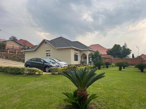 grande villa verdoyante à louer pour 1 mois في كيغالي: منزل به سيارة متوقفة في ساحة