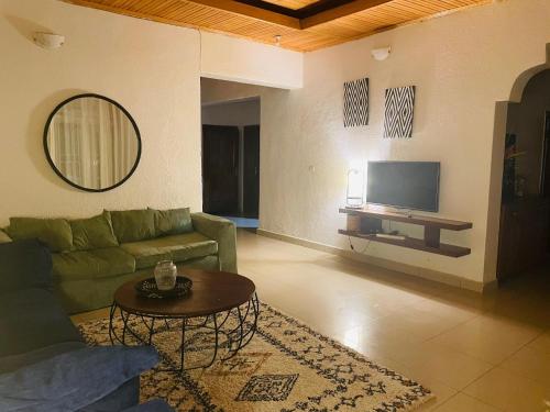 uma sala de estar com um sofá verde e uma televisão em grande villa verdoyante à louer pour 1 mois em Kigali
