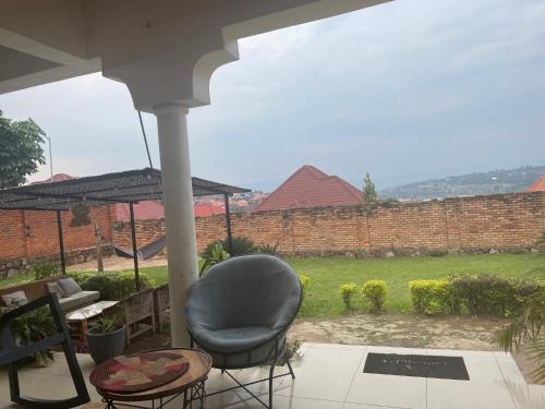 grande villa verdoyante à louer pour 1 mois في كيغالي: كرسي جالس على شرفة المنزل