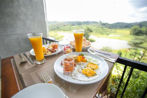 a table with a plate of food and two glasses of orange juice at Sueen Nature Resort in Hatton