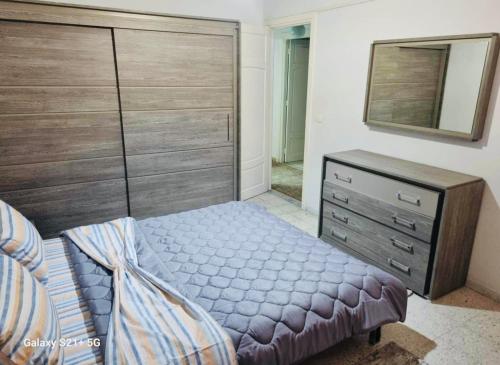 um quarto com uma cama, uma cómoda e um espelho em Superbe logement Majida boulila em Sfax