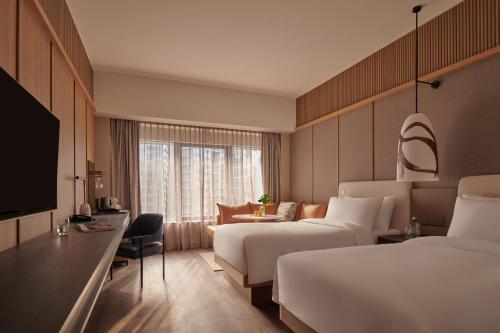 a hotel room with two beds and a television at Amara Singapore in Singapore