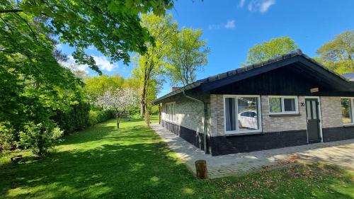 a small house in a garden with a grass yard at Gezellige, luxe bungalow 't pareltje in het bos in Hardenberg "Rheezerveen"woning 20 in Rheezerveen