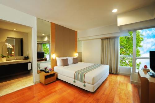 a bedroom with a large bed and a large window at Somerset Berlian Jakarta in Jakarta