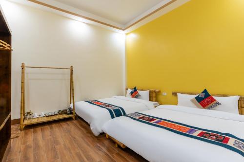 two beds in a room with yellow walls and wooden floors at Sapa Heaven House in Sa Pả