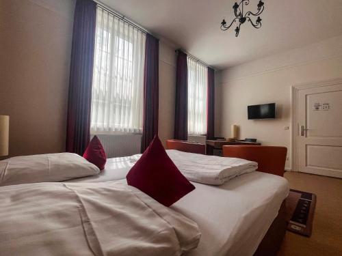 Habitación de hotel con 2 camas con almohadas rojas en Apartmenthaus Gutenberg 78, en Potsdam