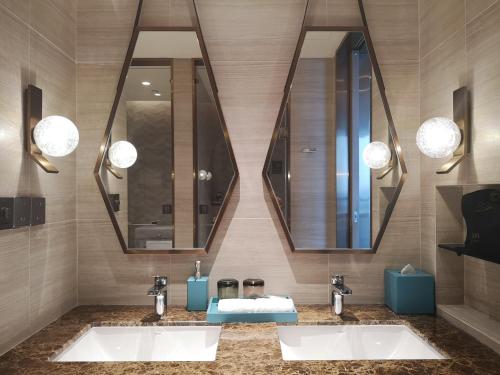 a bathroom with two sinks and two mirrors at L+Snow Supreme Hotel in Shanghai