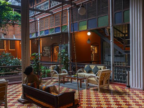 a person sitting in a chair on a patio at The House of MG-A Heritage Hotel, Ahmedabad in Ahmedabad