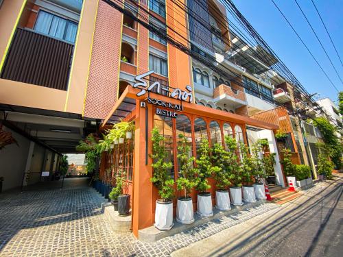 SO Zen Hotel Silom Bangkok في بانغ راك: مبنى أمامه مجموعة من النباتات الفخارية
