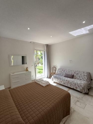 a bedroom with a bed and a couch and a window at Villetta Lu Sciardinu in Otranto