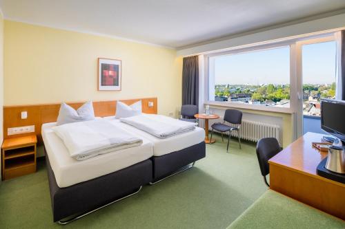 a hotel room with a bed and a desk and a window at Garden Hotel Krefeld in Krefeld