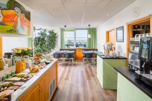 a large kitchen with a cafeteria with tables and chairs at Garden Hotel Krefeld in Krefeld