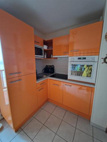 - une cuisine avec des armoires orange et un four micro-ondes dans l'établissement Appartement vue mer, à Cabourg
