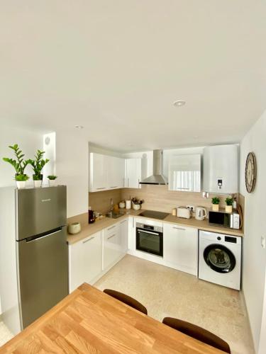 une cuisine avec des armoires blanches et une table en bois dans l'établissement T2 Boheme Centre Ville Palavas Proche Plage, à Palavas-les-Flots