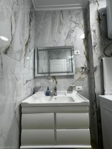 a white bathroom with a sink and a mirror at GOLEM Best Apartment in Golem