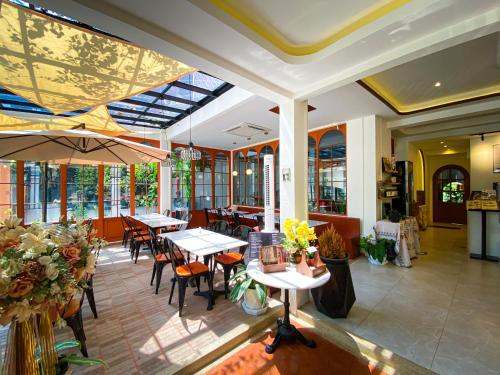 a restaurant with tables and chairs and windows at SO Zen Hotel Silom Bangkok in Bang Rak