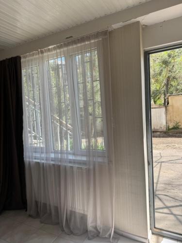 Apartment on Vazha-Pshavela VI, 1A في تبليسي: نافذة مع ستائر بيضاء في الغرفة