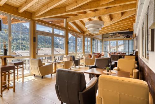 a restaurant with tables and chairs and windows at Hotel Alpen-Royal in Jerzens