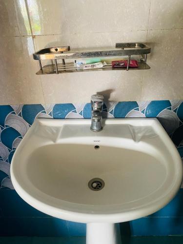 a white sink in a bathroom with blue tiles at Hong Qi Hotel in Chitwan