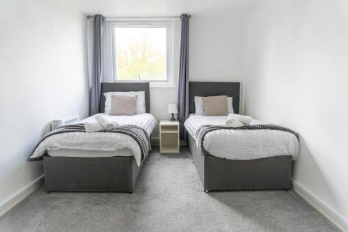 two twin beds in a room with a window at 2 Bed - City Centre Apartment - Long Stay Rates - Perfect for Families, Contractors and Professionals in Leeds