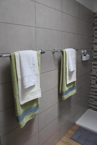 La salle de bains est pourvue de serviettes blanches accrochées au mur. dans l'établissement APARTAMENTOS CANAIMA, à Puerto Rico