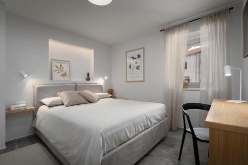 Habitación blanca con cama y escritorio en Grotta Apartment en Vrsar