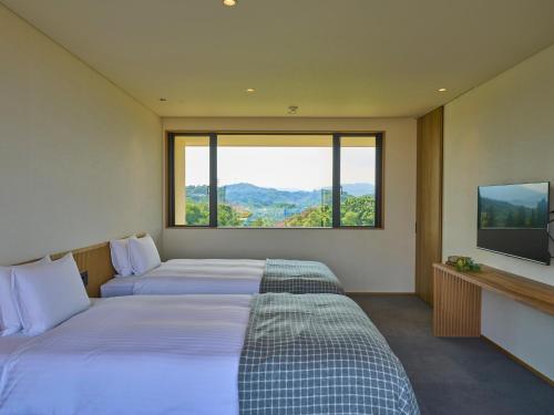 two beds in a room with a large window at Setouchi Resort Villa - Vacation STAY 07952v in Takekara