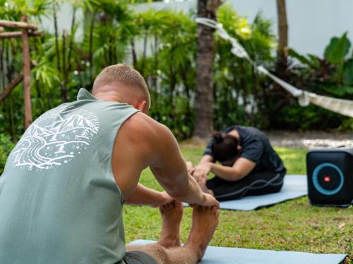 a man doing yoga with a woman in the background at Explorar Koh Samui - Adults Only Resort and Spa in Mae Nam
