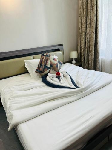 a bed with white sheets and towels on it at Greenlight Apartments in Kiembi Samaki