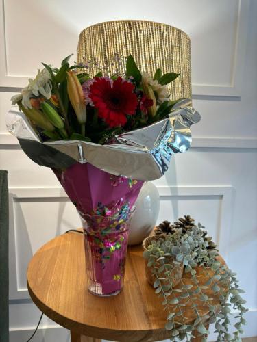 a vase of flowers on a table with a chair at Apartamentos Turísticos La Plaza in Chipiona