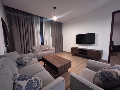 sala de estar con sofás y TV de pantalla plana. en غرفة مع صالة رايقة في ملنينيوم en Salalah