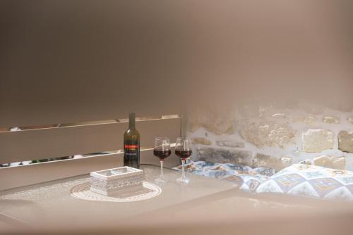 a bottle of wine and two glasses on a bed at Faidra House in Vóroi